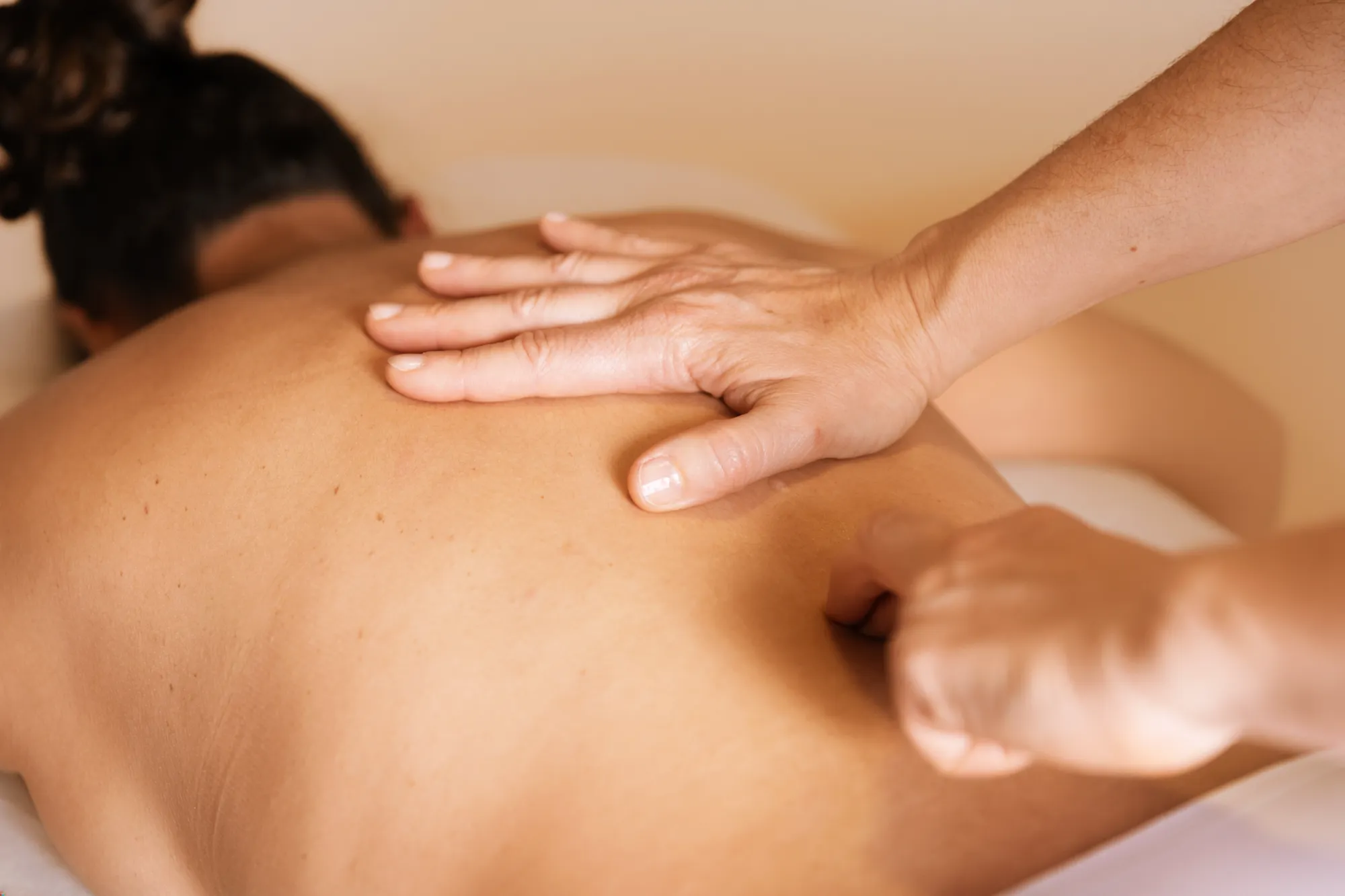 Técnica de masaje manual aplicada en la zona media de la espalda de una paciente.