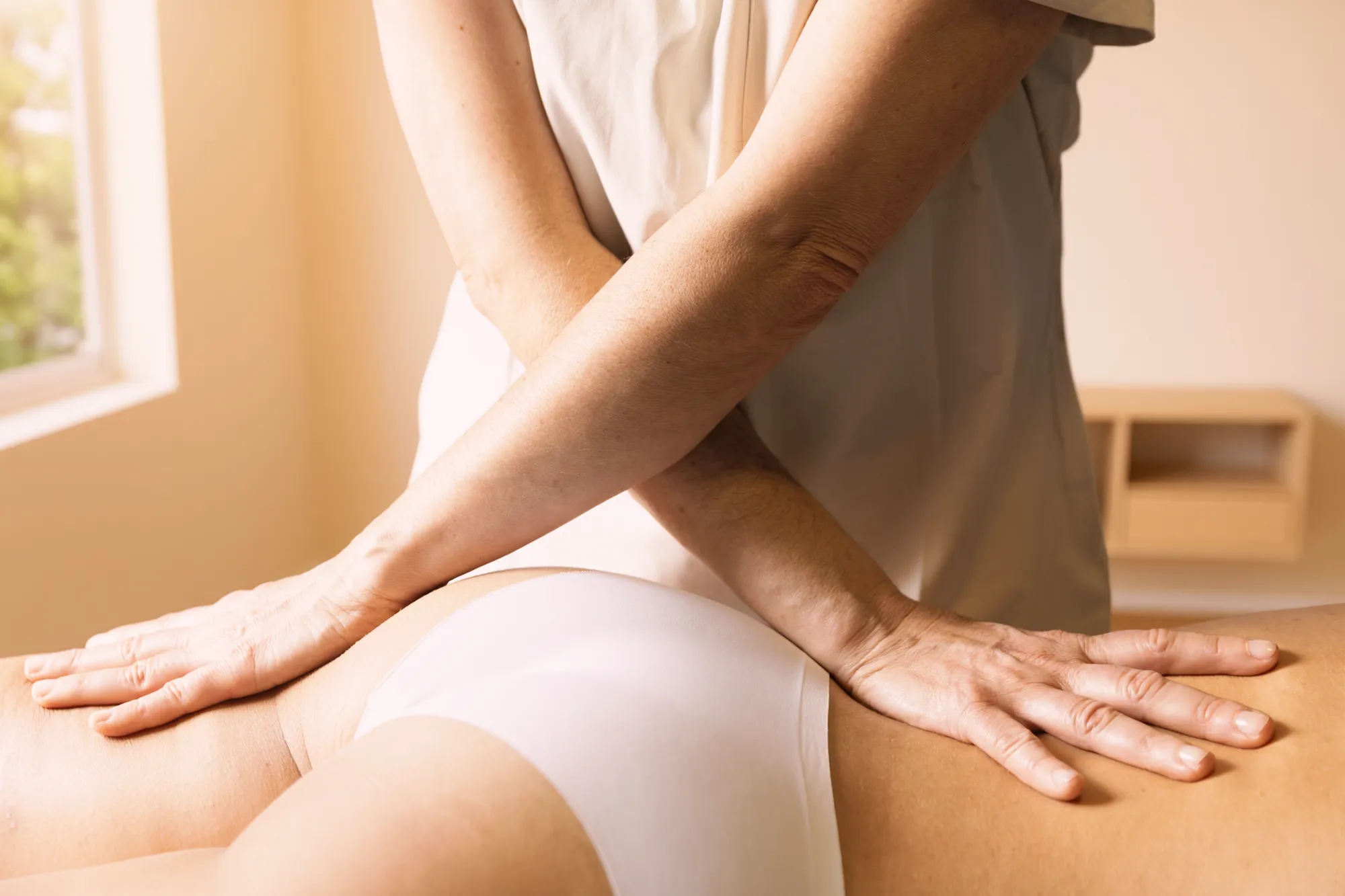 Manos de Gemma Fernández aplicando presión terapéutica en la zona lumbar de una paciente.