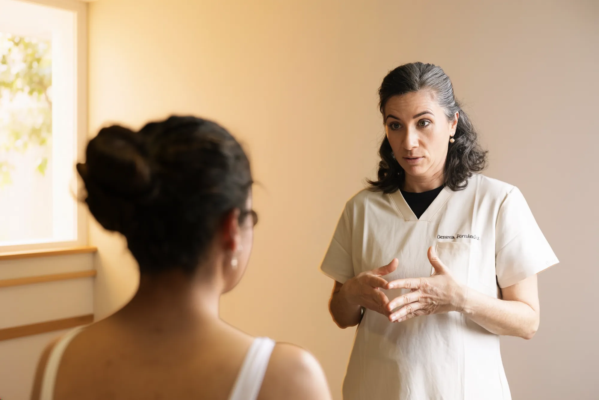 Gemma Fernández explicando un tratamiento a una paciente durante una consulta clínica.